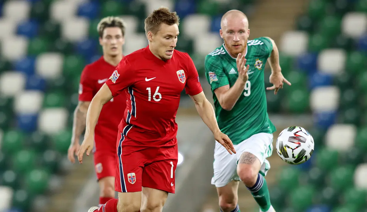 Bek Norwegia, Jonas Svensson, berebut bola dengan penyerang Irlandia Utara, Liam Boyce, pada laga UEFA Nations League di Windsor Park, Selasa (8/9/2020) dini hari WIB. Norwegia menang telak 5-1 atas Irlandia Utara. (AFP/Paul Faith)