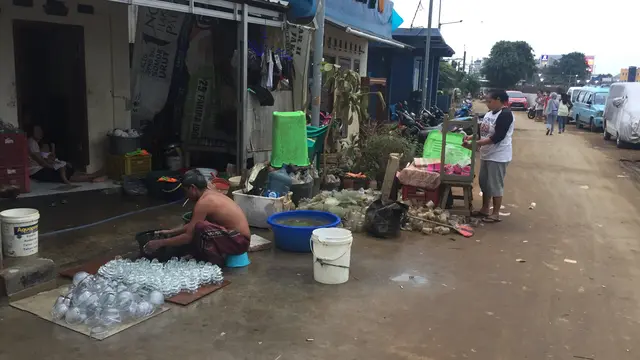 Warga mencuci gelas yang terendam banjir.