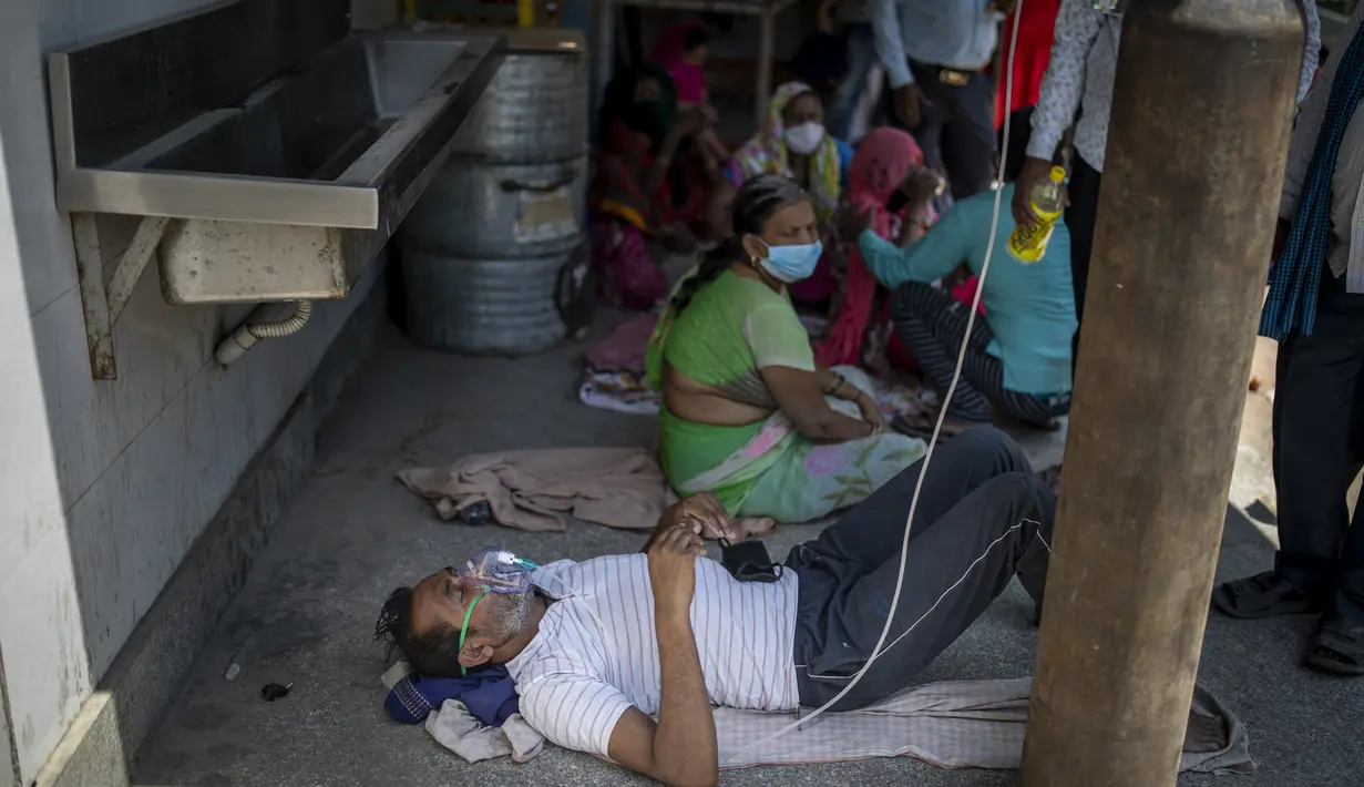 Seorang pasien menerima oksigen di luar Gurdwara, rumah ibadah Sikh, di New Delhi, India, pada  24 April 2021. Pemerintah India berjuang untuk mendapatkan pasokan oksigen ke rumah sakit yang kewalahan oleh ratusan ribu kasus harian baru setiap harinya. (AP Photo/Altaf Qadri)