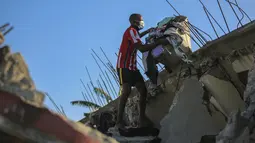 Seorang pria mengambil barang-barang dari rumahnya yang hancur akibat gempa di Les Cayes, Haiti, Sabtu (14/8/2021). Wilayah Negara Haiti diguncang gempa berkekuatan magnitudo 7,1 pada Sabtu, 14 Agustus 2021 pukul 08.29.10 waktu setempat yang menewaskan lebih dari 300 jiwa. (AP Photo/Joseph Odelyn)
