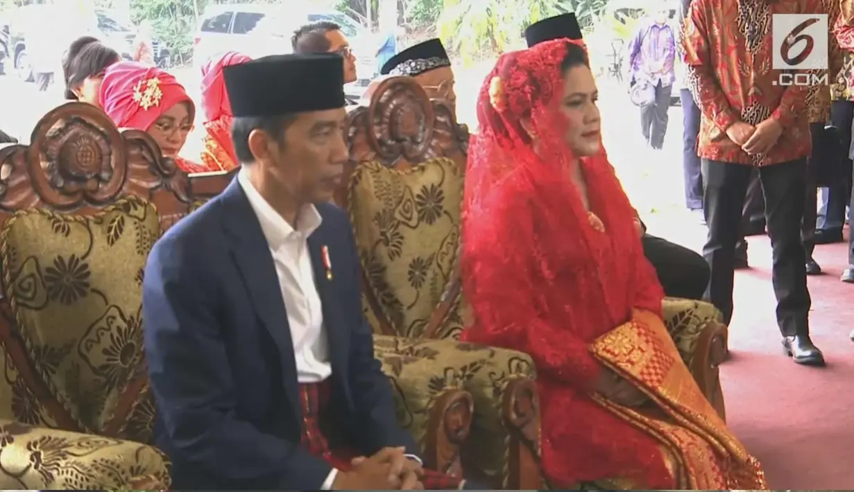 Presiden Joko Widodo dan Ibu Negara Iriana mendengarkan sambutan saat mengikuti prosesi penyambutan keluarga mempelai wanita secara adat di Bukit Hijau Regency Taman Setia Budi (BHR Tasbi), Medan, Sabtu (25/11). (Liputan6.com/vidio)