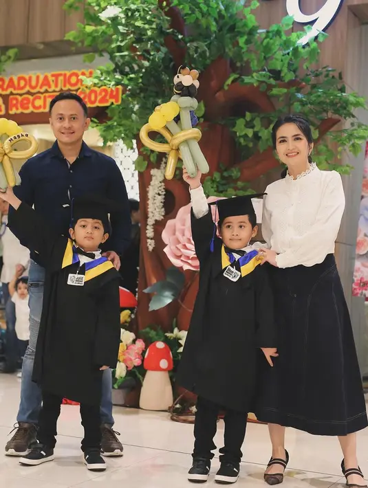Bangga kepada sang buah hati yang sebentar lagi akan masuk SD, Kadek dan Dewa juga memberikan ciuman sayang kepada Magha dan Degha. Dalam momen tersebut, Kadek Devi tampil elegan dengan atasan putih dan bawahan rok berwarna hitam. (Liputan6.com/IG/@dewayoga_07)