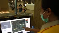 Salah satu petugas Kantor Kesehatan Pelabuhan Kelas I Denpasar menunjukan cara kerja alat pengukur suhu tubuh otomatis yang berada di titik kedatangan bagi para delegasi dan wisatawan asing di Bandara I Gusti Ngurah Rai, Bali, pada Senin (14/11/2022). (Foto: Dok BNPB)
