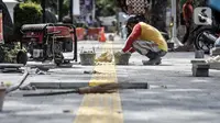Pekerja menyelesaikan proyek revitalisasi trotoar di Jalan Medan Merdeka Selatan, Jakarta Pusat, Selasa (22/11/2022). Pemprov DKI Jakarta mengalokasikan anggaran sebesar Rp 171 miliar dalam Rancangan Anggaran Pendapatan dan Belanja Daerah (RAPBD) DKI Jakarta 2023 untuk revitalisasi trotoar di Ibu Kota. (merdeka.com/Iqbal S. Nugroho)