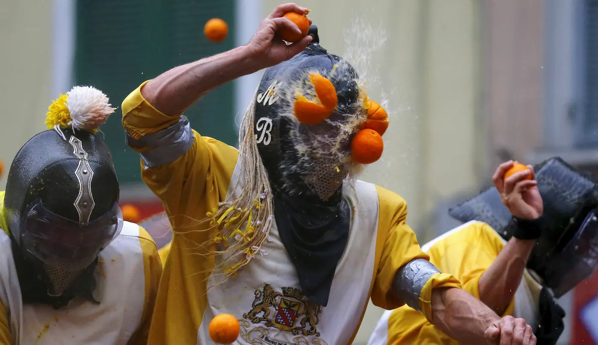 Seorang peserta dilempari jeruk saat perang-perangan selama karnaval di kota Ivrea, Italia, Minggu (7/2). Peserta yang dibagi menjadi dua tim ini saling melempar jeruk menggunakan kostum dan aksesoris lengkap. (REUTERS/Stefano Rellandini)