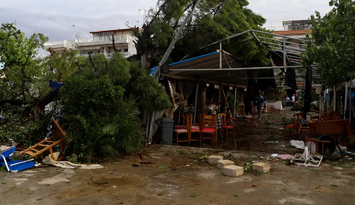 Warga berjalan dalam restoran setelah badai menerjang Desa Nea Plagia, Halkidiki, Yunani, Kamis (11/7/2019). Menurut para ahli, badai ekstrem tersebut melanda setelah Yunani mengalami lonjakan suhu hingga 37 derajat Celsius selama dua hari di awal pekan ini. (Giannis Moisiadis/InTime News via AP)