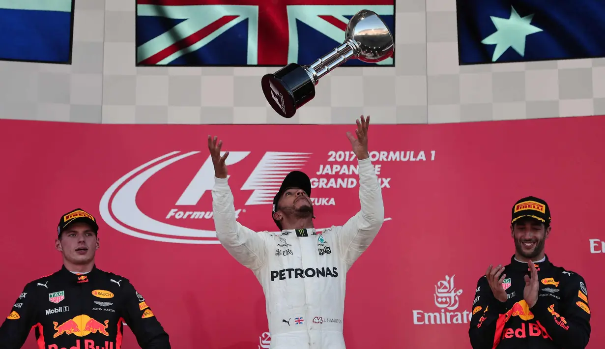 Pembalap F1 dari tim Mercedes Lewis Hamilton dari Inggris melakukan selebrasi di atas podium bersama pembalap Red Bull Daniel Ricciardo (kanan) dan Max Verstappen usai berlaga di GP F1 Jepang di Sirkuit Suzuka, Jepang, (8/10). (AFP Photo/Behrouz Mehri)