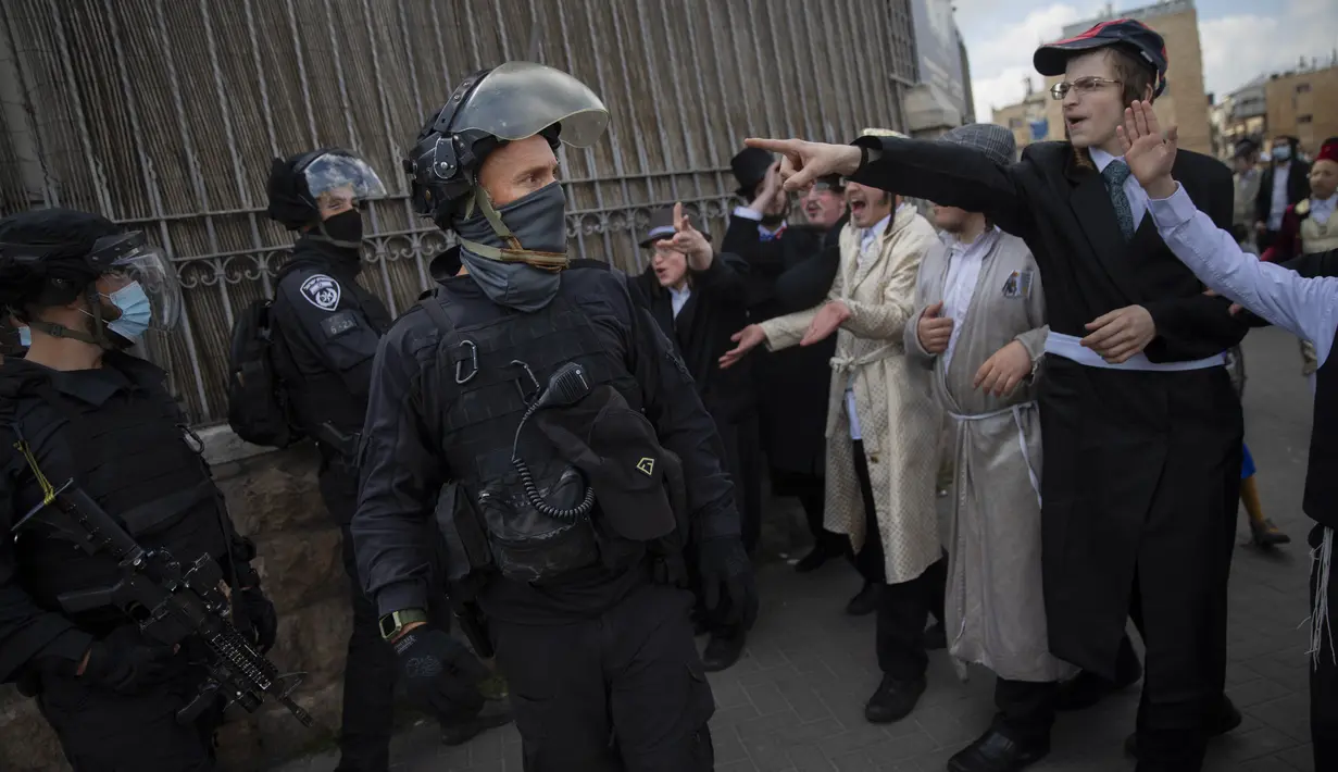 Beberapa orang Yahudi Ultra-Ortodoks mengenakan kostum bentrok dengan petugas polisi selama perayaan hari libur Yahudi Purim, di lingkungan ultra-Ortodoks Mea Shearim Yerusalem (28/2/2021). (AP Photo/Oded Balilty)