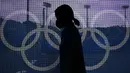 Seorang petugas lapangan melewati jaring yang dihiasi dengan Cincin Olimpiade di lapangan utara Stadion Hoki Oi sebelum pertandingan hoki lapangan wanita antara Argentina dan Jerman di Olimpiade Musim Panas 2020 di Tokyo, Jepang, Selasa (2/8/2021). (AP Photo/John Locher)