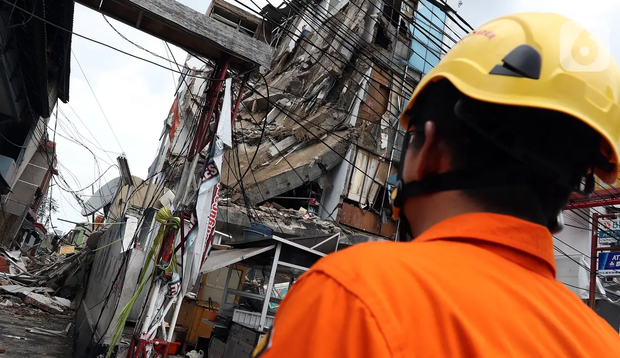 Petugas Basarnas mengamati gedung yang ambruk di Jalan Brigjen Katamso, Kota Bambu Selatan, Palmerah, Jakarta Barat, Senin (6/1/2020). Tiga orang dilaporkan terluka akibat tertima material gedung empat lantai tersebut. (Liputan6.com/Johan Tallo)