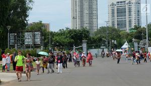 Sejumlah pengunjung berjalan saat sedang liburan di Monumen Nasional (monas), Jakarta, Selasa (25/12). Liburan Natal 2018, banyak warga datang bersama kerabat maupun keluarga memadati Monas. (Liputan6.com/Herman Zakharia)