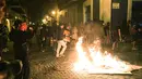 Para pengunjuk rasa membakar sampah saat bentrok dengan polisi di Old San Juan, Puerto Rico (22/7/2019). Para pengunjuk rasa menuntut agar Gubernur Ricardo Rossello mundur  dari jabatannya setelah dalam pusaran skandal pesan teks daring tak senonoh dengan para stafnya. (AFP Photo/Joe Raedle)