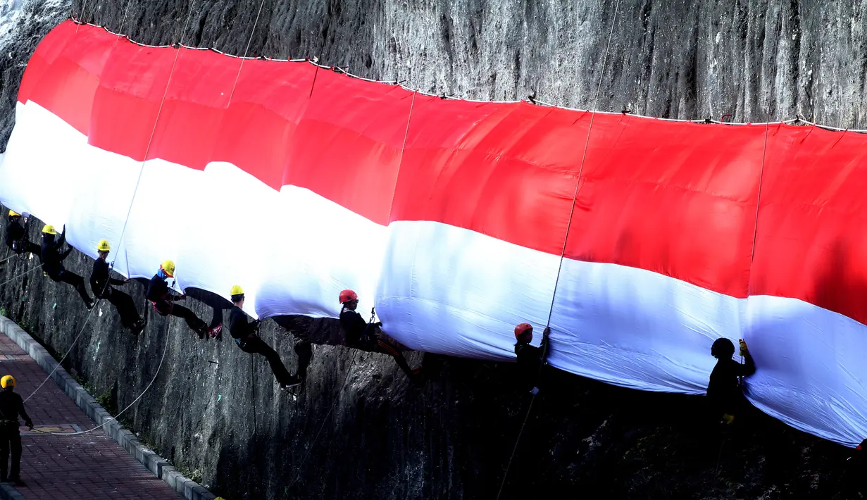 Anggota Brimob Polda Bali dan Basarnas mengibarkan Bendera Merah Putih di dinding tebing Pantai Pandawa, Badung, Bali, Senin (14/8). Pengibaran Bendera Merah Putih sepanjang 800 meter tersebut untuk memperingati HUT RI ke-72. (AP Photo/Firdia Lisnawati)