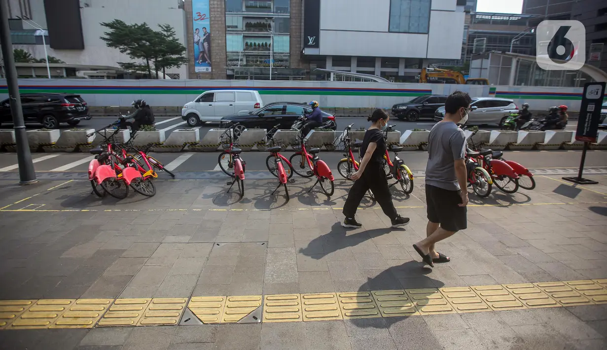 Pejalan kaki melintas dekat deretan sepeda Gowes di kawasan Bundaran HI, Jakarta, Selasa (28/6/2022). Tak terawatnya layanan sepeda sewa (bike sharing) membuat pedestrian kawasan Bundara HI tampak kotor karena jejeran layanan sepeda sewa tak terurus. (Liputan6.com/Faizal Fanani)