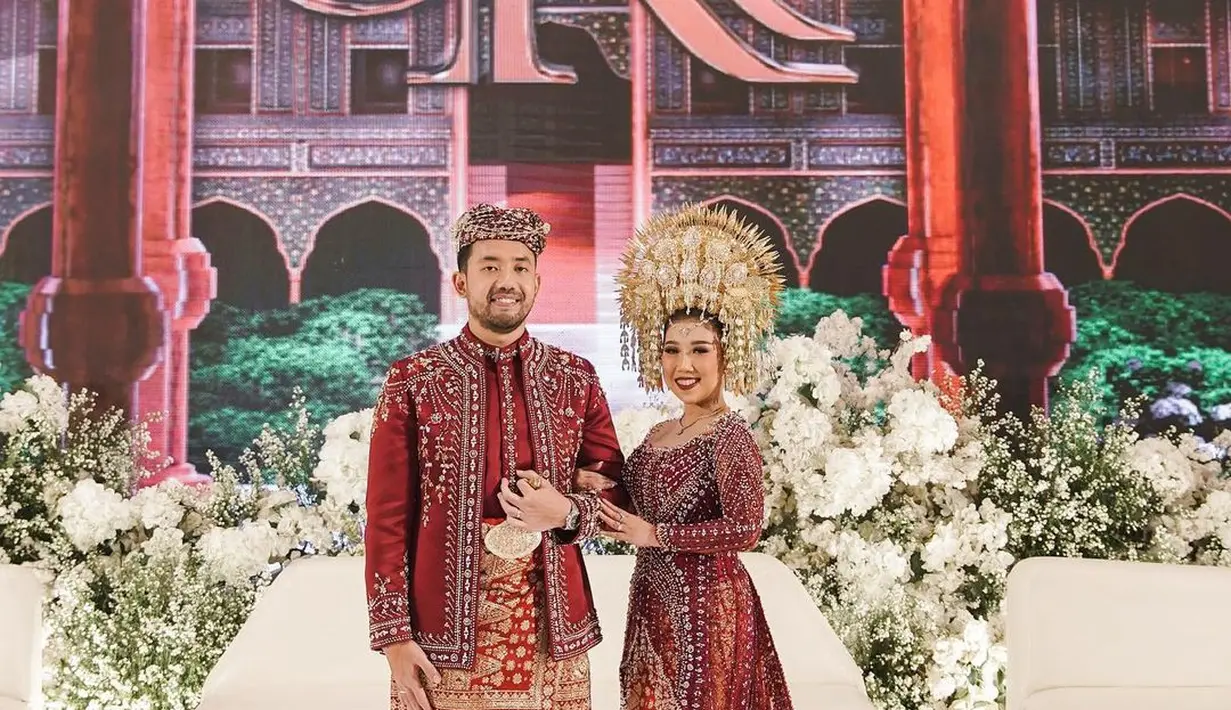 Penampilan megah Kiky Saputri mengenakan kebaya adat Minang. Kebaya megah berwarna merah yang dikenakan Kiky di acara resepsi pernikahannya ini, memiliki detail taburan payet yang membuat penampilannya semakin berkilauan, dengan sambungan train panjang menjuntai ke lantai. Kebaya ini dipadu dengan kain bernuansa merah keemasan yang serasi. [Foto: Instagram/kikysaputrii]