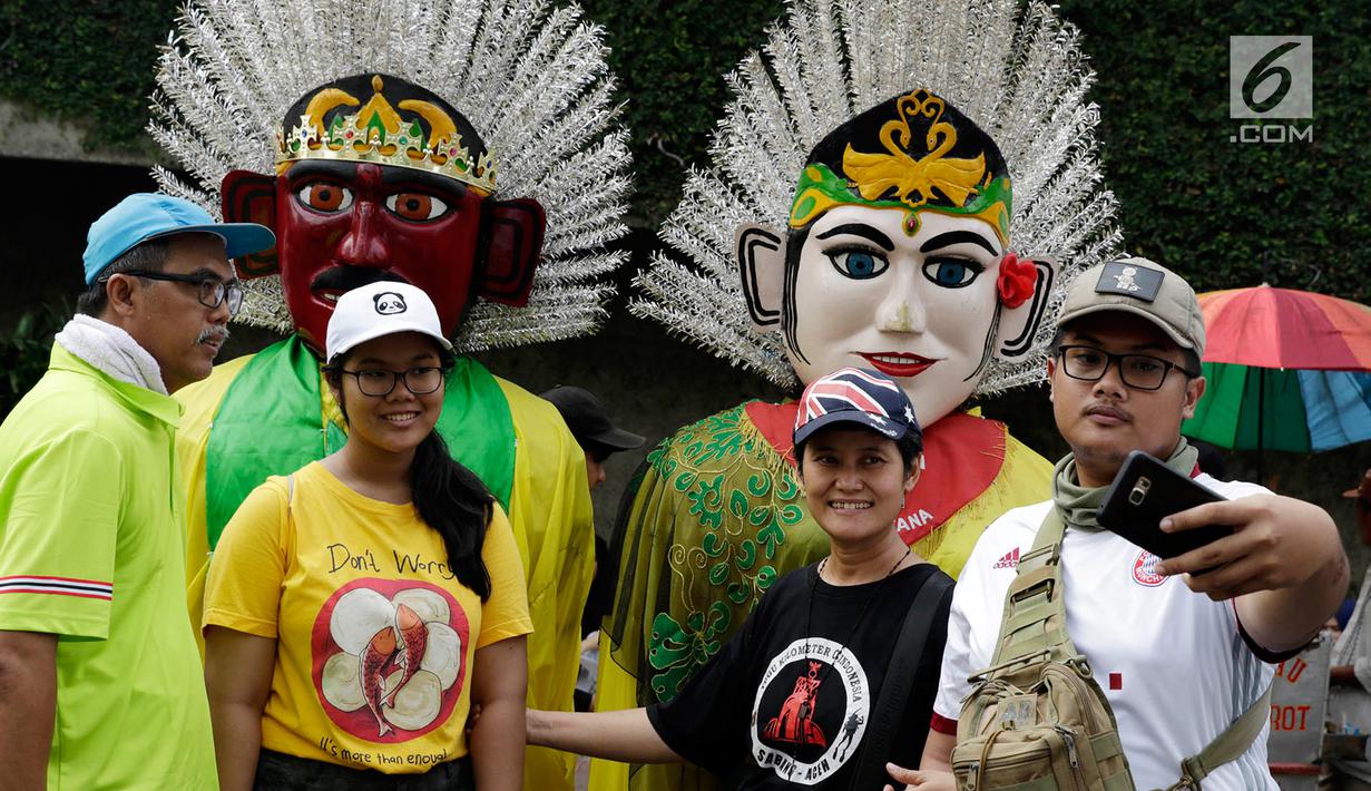 Sejumlah warga berfoto bersama ondel-ondel di lokasi car free day (CFD), Jakarta, Minggu (21/5). Ramainya pengunjung CFD menyebabkan banyak pengamen mencari rezeki di kegiatan yang berlangsung rutin setiap minggu tersebut. (Liputan6.com/Immanuel Antonius)