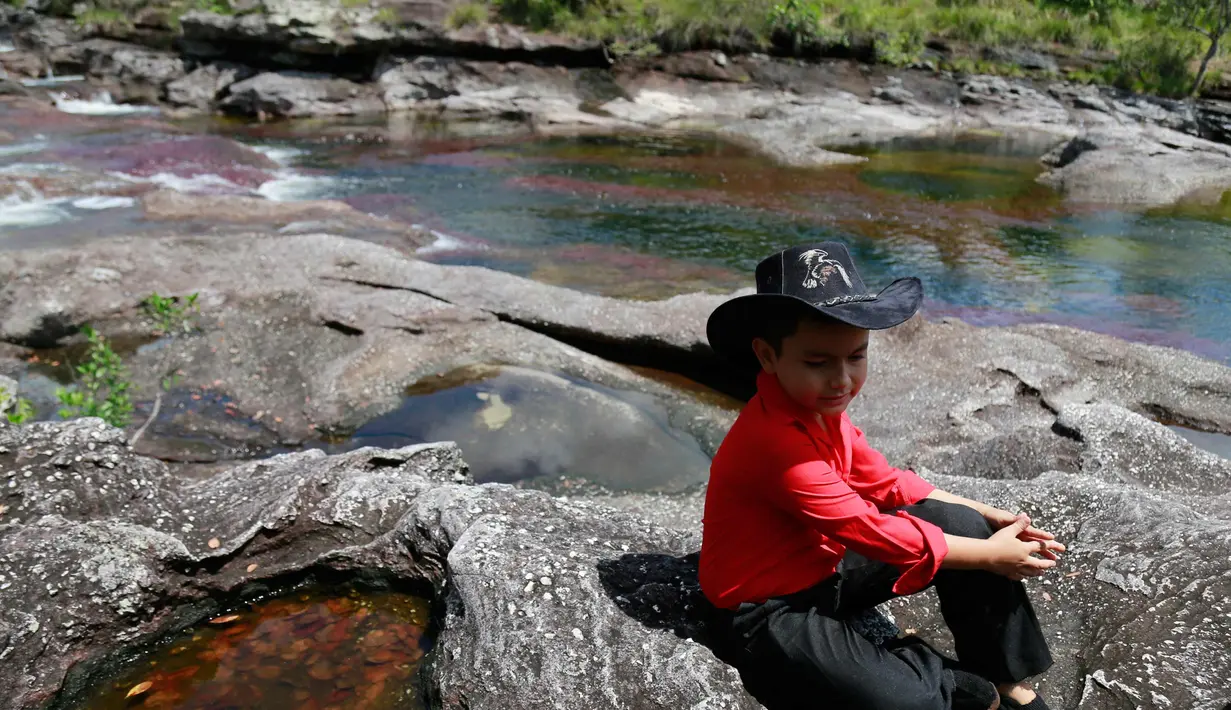 Seorang anak saat duduk santai di bebatuan Sungai Cano Cristales atau disebut "sungai lima warna" terlihat di Taman Nasional Sierra de La Macarena, provinsi Meta, Kolombia (27/9). (AFP PHOTO/John Vizcaino)
