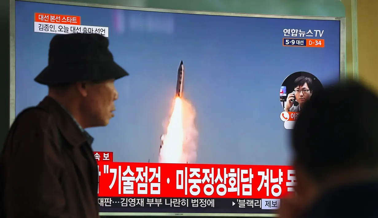 Seorang pria melewati layar televisi yang menyiarkan berita peluncuran rudal oleh Korea Utara (Korut), di sebuah stasiun kereta di Seoul, Korea Selatan, Selasa (5/4). Rudal itu ditembakkan dari wilayah timur Korut ke arah Laut Jepang. (JUNG Yeon-Je/AFP)