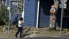 Seorang anak melihat pohon mangga yang dilukis oleh Gonzalo Sanchez di sudut jalan di lingkungan Escazu, Kosta Rika, Selasa (1/3). Lukisan bernama "The Woman in Red Bikini" itu menirukan sosok wanita yang mengenakan bikini. (REUTERS/Juan Carlos Ulate)