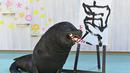 Singa laut Leo menggunakan kuas untuk melukis karakter China "harimau", yang merupakan tanda zodiak China tahun baru yang akan datang, selama pratinjau pers di Hakkeijima Sea Paradise di Yokohama (27/12/2021). (AFP/Kazuhiro Nogi)