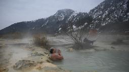 Seorang pria menikmati air panas di mata air mineral alami pada hari musim dingin di dekat desa Rupite, Bulgaria (2/2/2022). Penduduk setempat percaya bahwa air mineral menyembuhkan banyak penyakit dan gangguan. (AFP/Nikolay Doychinov)