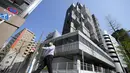 Seorang pria berjalan di depan lokasi pembongkaran Nakagin Capsule Tower, bangunan ikonik yang dirancang arsitek Jepang Kisho Kurokawa pada tahun 1972, di distrik Ginza Tokyo, Selasa (12/4/2022). Pekerjaan pembongkaran menara 140 unit kapsul tersebut dimulai Selasa. (AP Photo/Eugene Hoshiko)