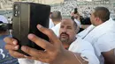 Seorang jemaah haji melakukan panggilan video ke kerabatnya dari Jabal Rahmah di Padang Arafah, dekat Kota Suci Mekkah, Arab Saudi, 8 Juli 2022. (AP Photo/Amr Nabil)
