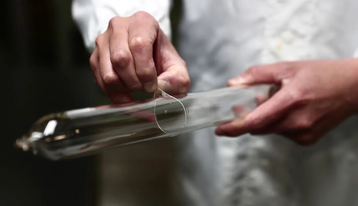 Pekerja memasukan tabung ke dalam kondom saat malukan uji kualitas di Sagami Rubber Industries, Prefektur Kanagawa, Jepang (25/1). Pada tahun 2013, perusahaan ini telah membuat kondom yang memiliki ketebalan 0,01 mm. (AFP Photo/Behrouz Mehri)