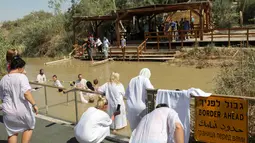 Umat Kristen mengikuti prosesi pembaptisan di Sungai Yordan, Jericho, Palestina, Jumat (13/9/2019). Kegiatan ini untuk mengenang prosesi pembaptisan Yesus Kristus oleh Yohanes Pembaptis. (HAZEM BADER/AFP)