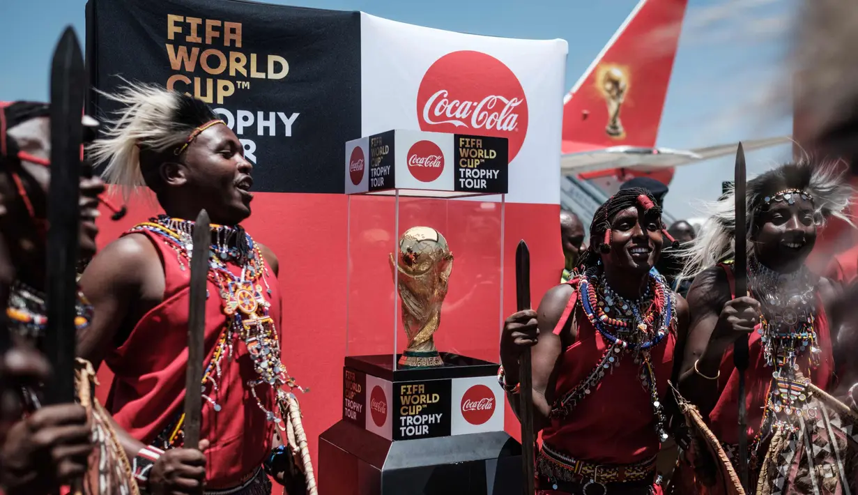 Penari suku Maasai Kenya berpose dengan trofi Piala Dunia FIFA selama Tur Dunia di bandara Internasional Jomo Kenyatta di Nairobi, Kenya (26/2). Turnamen Piala Dunia akan dimulai Juni di Rusia. (AFP Photo/Yasuyoshi Chiba)