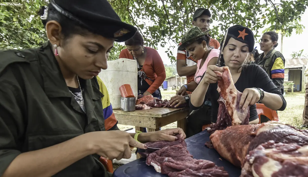 Sejumlah gerilyawati FARC memotong daging di kamp Magdalena Medio, Kolombia (15/3/2016). Gerilyawati FARC dikenal lebih sadis terhadap musuh daripada pasukan gerilyawan. (AFP Photo/Luis Acosta)