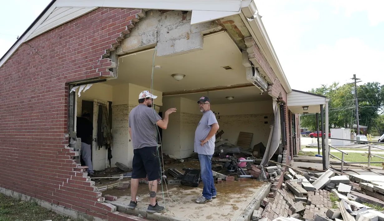 Brian Mitchell (kanan) melihat-lihat rumah ibu mertuanya yang rusak akibat banjir di Waverly, Tennessee, Minggu (22/8/2021). Sejumlah mobil dan rumah warga tersapu banjir di jalanan Waverly, kota yang berjarak sekitar 90 kilometer dari Nashville. (AP Photo/Mark Humphrey)