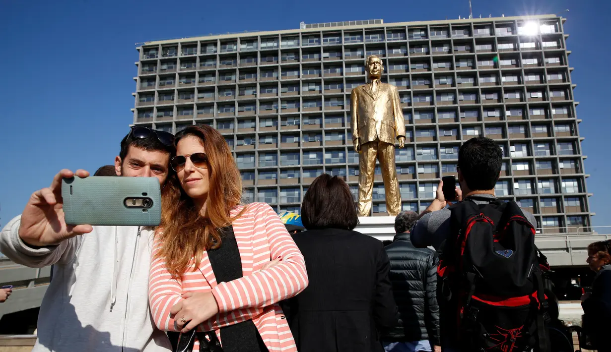 Warga berselfie dan mengabadikan patung emas raksasa PM Israel Benjamin Netanyahu di tengah-tengah Rabin Square, Tel Aviv, Selasa (6/12). (REUTERS / Baz Ratner)