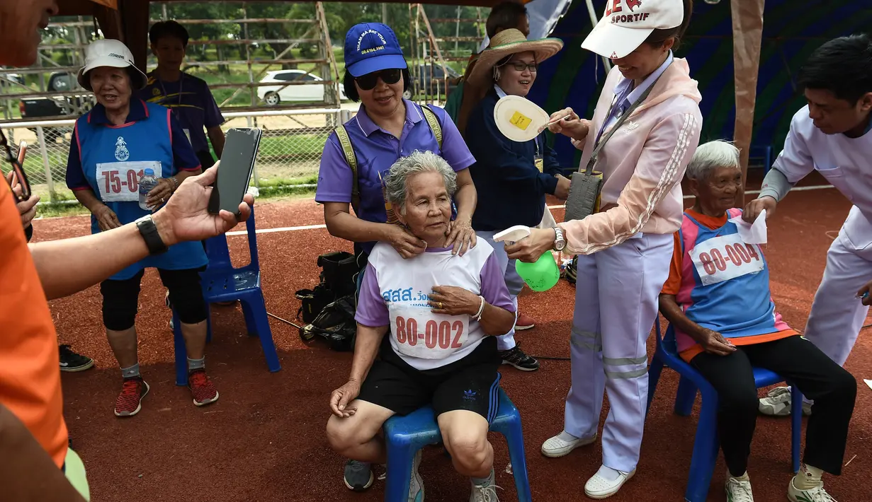 Seorang wanita lansia berusia 80 tahun, Duangpee Sansing (tengah) beristirahat usai memenangkan perlombaan sprint 400 meter dalam Elderly Games Nasional di Thailand (25/4). (AFP/Lillian Suwanrumpha)
