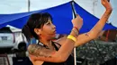 Seorang wanita mengambil gambar kuncup untuk merayakan legalisasi ganja di "Thailand: 420 Legalaew!" festival akhir pekan yang diselenggarakan oleh Highland di provinsi Nakhon Pathom pada 11 Juni 2022. (AFP/Lillian Suwanrumpha)