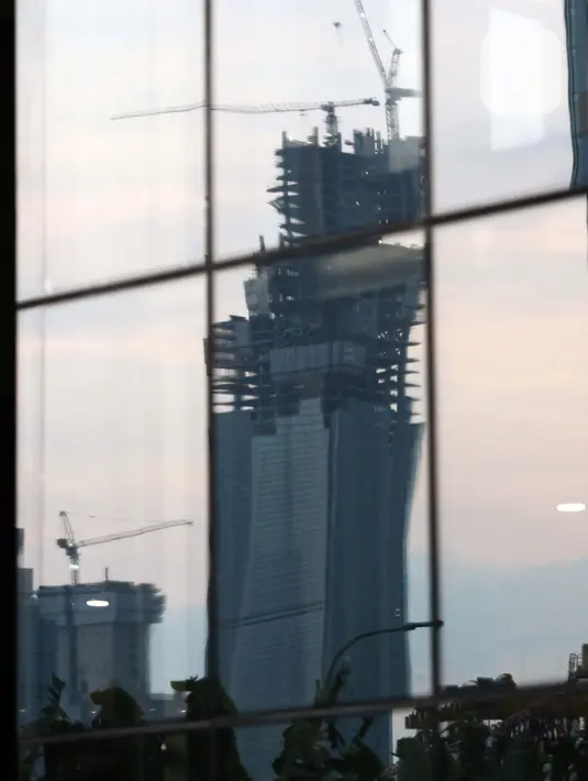 Refleksi pembangunan gedung bertingkat di kawasan Kuningan, Jakarta, Rabu (8/7/2020). Wabah Covid-19 memengaruhi kondisi kesejahteraan masyarakat dan pertumbuhan ekonomi Indonesia pada tahun 2020 yang diproyeksikan -0,4 sampai dengan 1,0 persen. (Liputan6.com/Helmi Fithriansyah}
