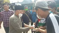 Ulama yang juga Youtuber asal Cirebon, Ujang Bustomi, membagikan uang kepada warga hingga petugas yang bertugas di sejumlah titik penyekatan PPKM Darurat. (Liputan6.com/ Panji Prayitno)