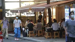 Orang-orang minum di bar selama keadaan darurat COVID-19 di Tokyo, Jepang pada Senin (12/7/2021). Status darurat keempat di Tokyo ini, yang berlaku hingga 22 Agustus, akan mencakup durasi gelaran Olimpiade Tokyo. (AP Photo/Koji Sasahara)