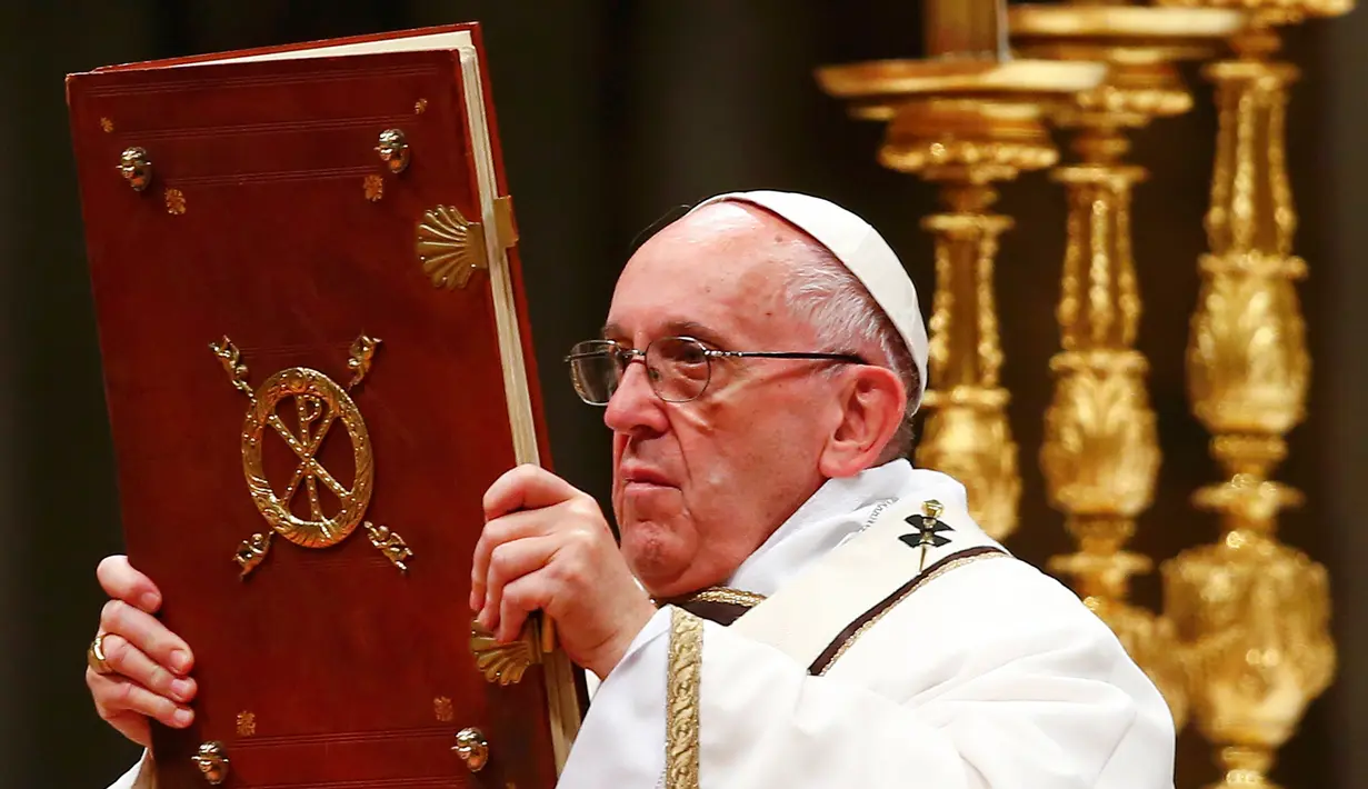 Paus Fransiskus memegang kitab Injil saat memimpin misa Natal di Basilika Santo Petrus, Vatikan, (24/12). Pada misa tersebut, Paus mengatakan bahwa Natal sudah "disandera" oleh materialisme. (REUTERS/Tony Gentile)