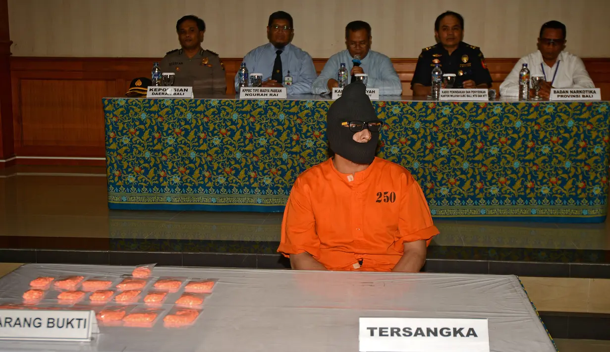 Mohd Husaini Jaslee berserta barang bukti diperlihatkan saat konferensi pers menyusul penahanannya di kantor pabean di Bandara Ngurah Rai, Denpasar (4/10). Jaslee ditangkap setelah membawah pil ekstasi di dalam tas laptopnya. (AFP Photo/Sonny Tumbelaka)