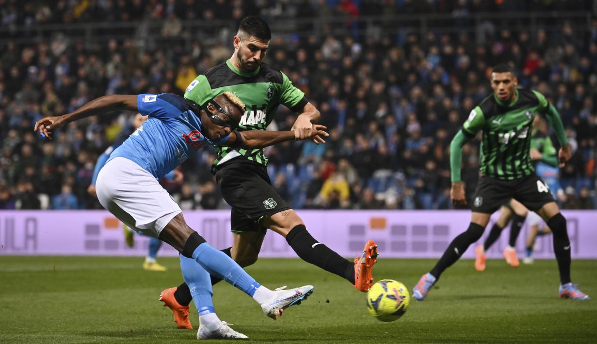 Pemain Napoli, Victor Osimhen (kiri) menendang bola dari sudut sempit ke gawang Sassuolo yang membuahkan gol dalam pertandingan pekan ke-23 Liga Italia 2022/2023 di Mapei Stadium, Sabtu (18/2/2023). (AFP/Marco Bertorello)