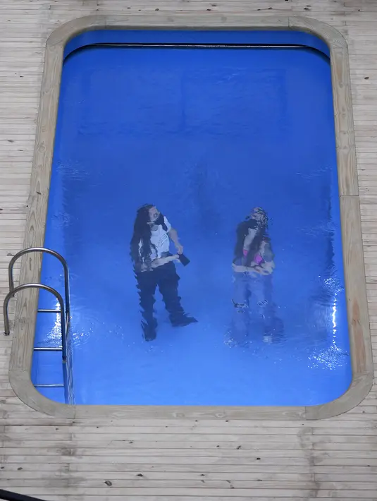 Pengunjung terlihat di dalam instalasi Kolam Renang" karya seniman Argentina, Leandro Erlich di Belo Horizonte, Brasil, Senin (20/9/2021). Pengunjung bisa memanfaatkan kolam renang ilusi ini dengan berjalan-jalan sambil menatap air beriak di atasnya atau hanya sekadar berfoto. (DOUGLAS MAGNO/AFP)