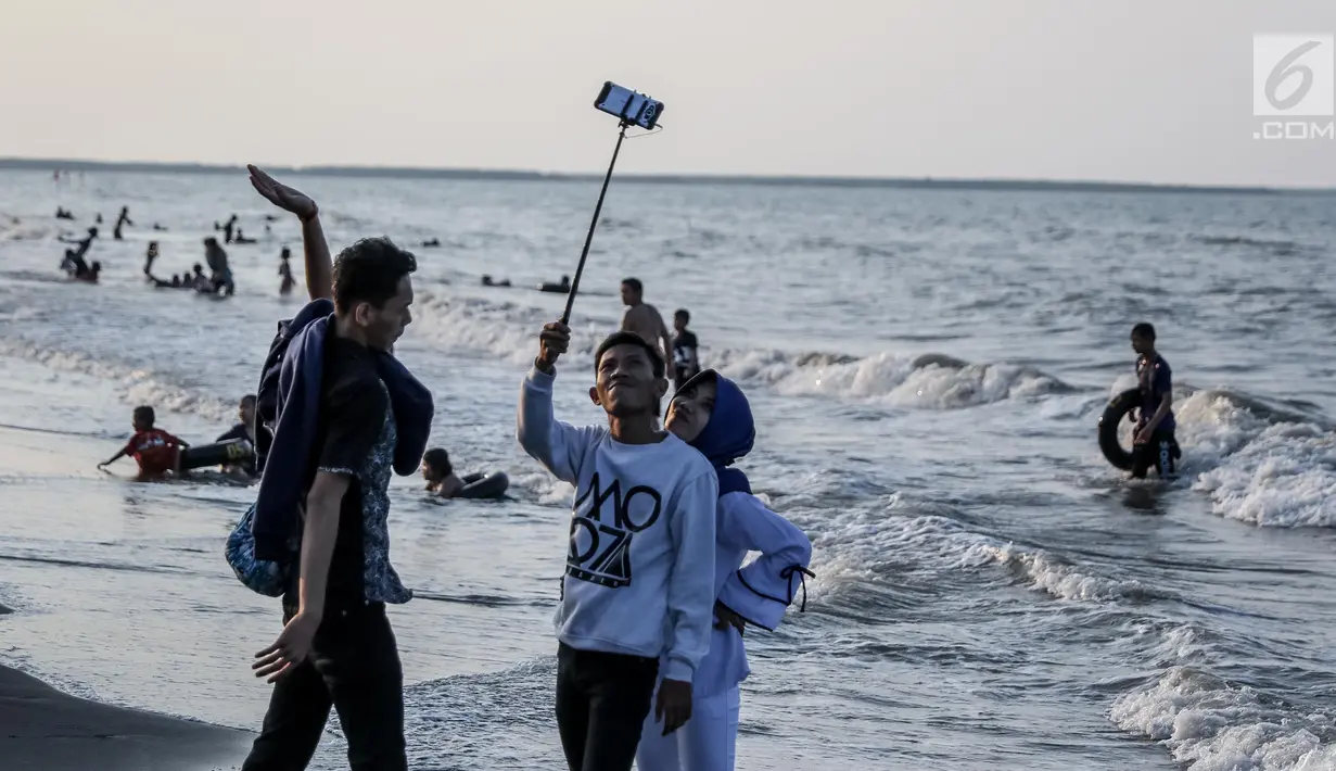 Pengunjung berswafoto di Pantai Randusanga Indah, Brebes, Jawa Tengah, Minggu (2/7). Pantai Randusanga Indah menjadi salah satu destinasi wisata bagi para pemudik yang melewati jalur Pantura. (Liputan6.com/Faizal Fanani)