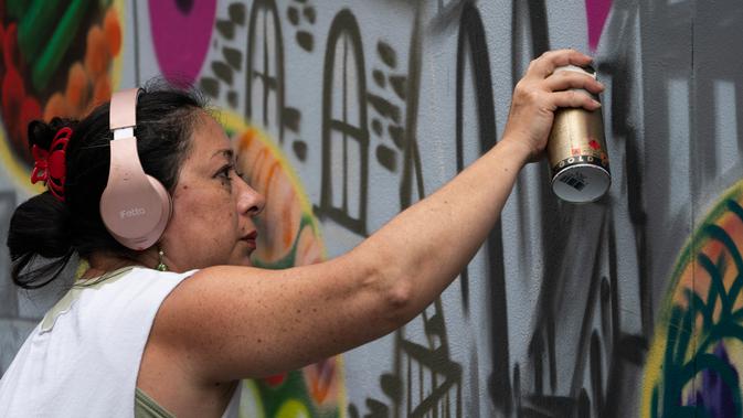 Seniman grafiti Sandra Fabara atau lebih dikenal Lady Pink melukis mural di Casita Maria, Bronx, New York, AS, Minggu (2/6/2019). Kesukaan Lady Pink terhadap dunia grafiti berawal saat dirinya melukis subway New York pada tahun 1979. (Don Emmert/AFP)
