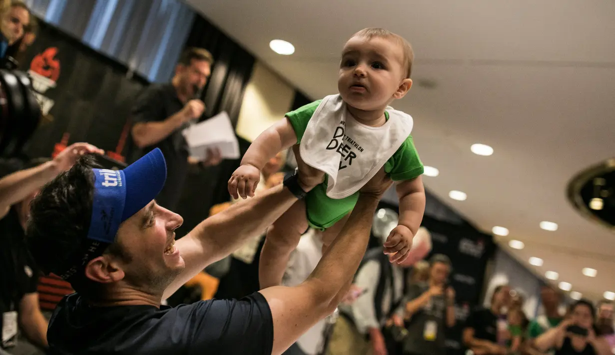 Seorang ayah mengangkat anaknya setelah mengikuti lomba merangkak dalam Diaper Derby NYC triathlon di New York City (14/7). (AFP Photo/Dominick Reuter)