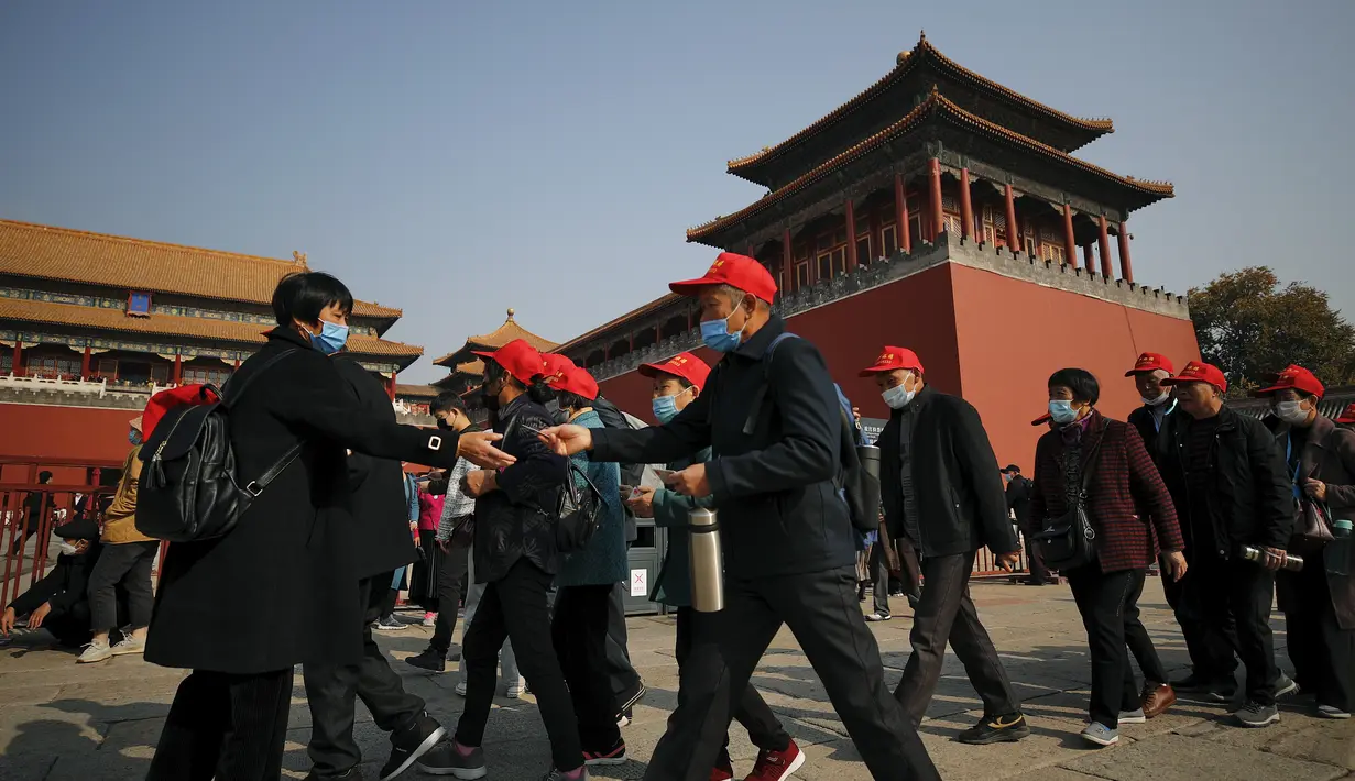 Turis mengenakan masker untuk mencegahn penyebaran virus corona hingga memasuki Kota Terlarang di Beijing (25/10/2020). Dengan wabah COVID-19 yang sebagian besar terkendali di dalam perbatasan China, rutinitas kehidupan sehari-hari yang normal telah mulai kembali untuk warganya. (AP Photo/Andy Wong)