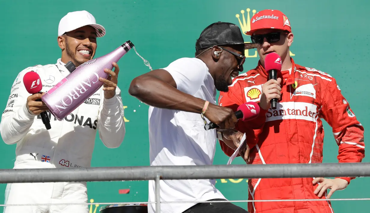 Pembalap Marcedes, Lewis Hamilton (kiri) menyiram sampanye ke mantan atlet lari cepat asal Jamaika, Usain Bolt saat merayakan kemenangannya di atas podium balapan GP Amerika Serikat di Circuit of Americas, Minggu (22/10). (AP Photo/Tony Gutierrez)