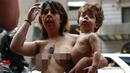 Seorang wanita sambil mengendong anaknya berpartisipasi dalam parade GoTopless di Manhattan, New York City, Minggu (23/8/2015). Aksi tersebut menuntut persamaan hak untuk bertelanjang dada seperti pria. (Kena Betancur/Getty Images/AFP)