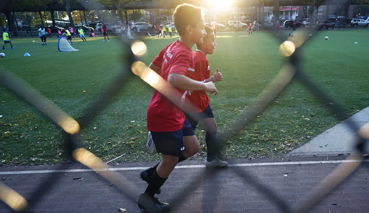 Dua anak laki-laki berlarian di sekitar trek di lingkungan Gravesend, Brooklyn, New York, Amerika Serikat, 28 September 2020.  Lebih dari 1 juta orang telah meninggal akibat COVID-19 di seluruh dunia hingga Selasa (29/9/2020). (AP Photo/Kathy Willens)