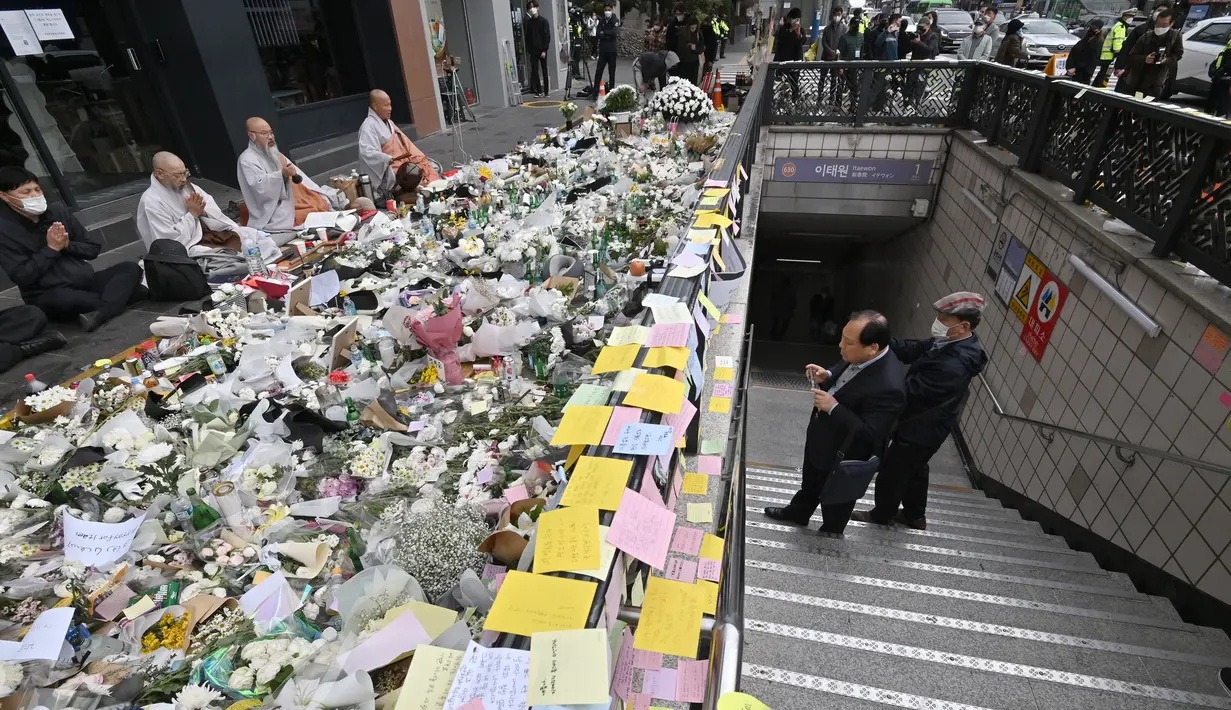 Biksu Buddha Korea Selatan (kiri) berdoa pada peringatan darurat untuk para korban akibat kerumunan massa dalam tragedi Halloween yang mematikan, di luar stasiun kereta bawah tanah di distrik Itaewon di Seoul, Kamis (3/11/2022). Hingga kini, pihak berwenang belum bisa menyimpulkan penyebab tragedi paling mematikan sejak 2014 lalu itu dan masih melakukan penyelidikan. (Jung Yeon-je / AFP)